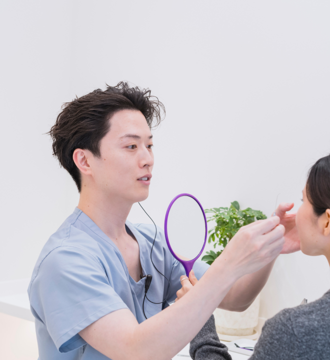 スリジエクリニックの医師が手鏡を使って丁寧にカウンセリングを行う様子